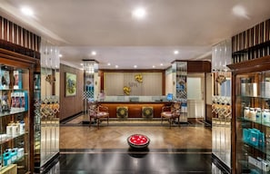 A reception area with a reception desk, two chairs, a decorative bowl, and glass display cases with products.
