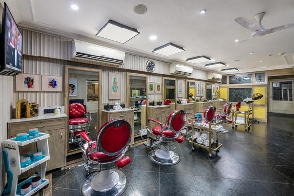 A salon with multiple red barber chairs, mirrors, and shelves with hair products. - Mayfair Lagoon Bhubaneswar (Bhubaneshwar)