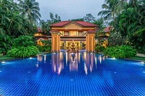 A large swimming pool with a fountain in the center, surrounded by lush greenery and a large building with a red roof. - Mayfair Lagoon Bhubaneswar (Bhubaneshwar)