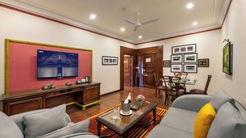 Una sala de estar con televisor, sofá, mesa de centro y comedor.