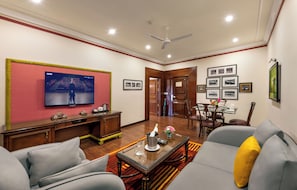 A living room with a television, sofa, coffee table, and dining area.