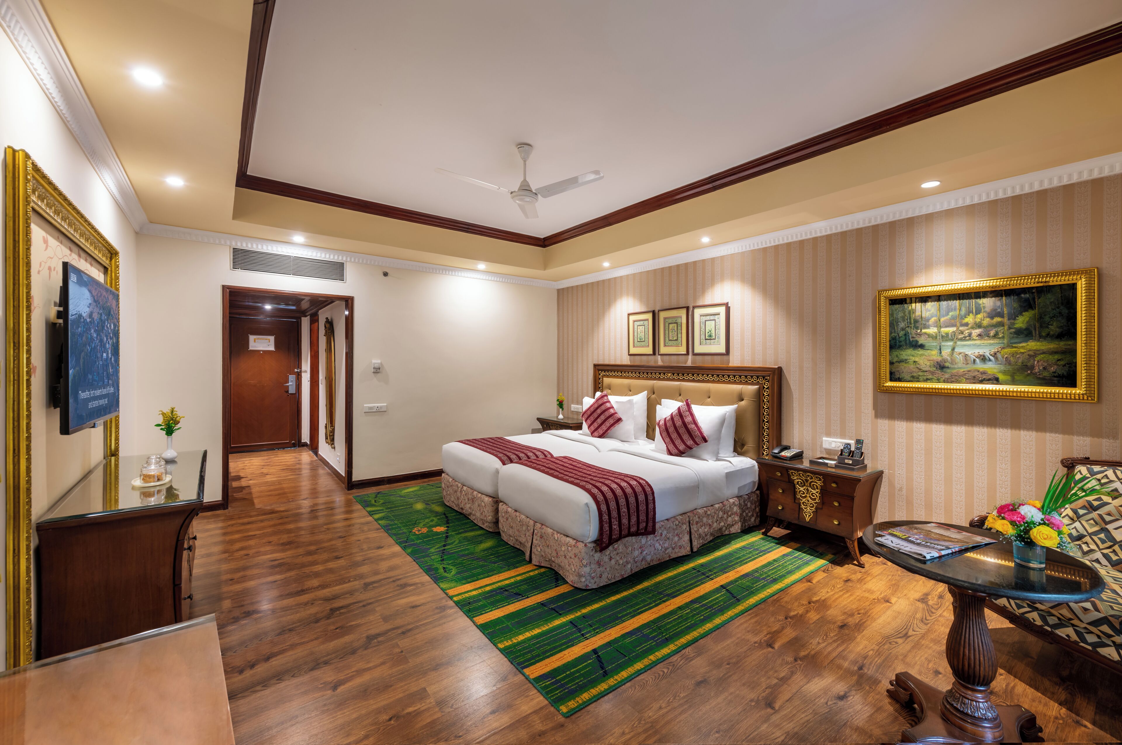 Une chambre d’hôtel avec un grand lit, une table à manger, un canapé et un ventilateur de plafond.