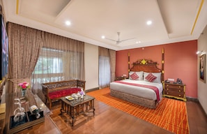 A bedroom with a bed, a nightstand, a wooden bench, a table with a vase of flowers, and a television.