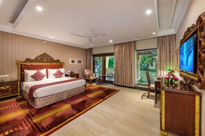 A hotel room with a large bed, a ceiling fan, a television, and a view of the outdoors. - Mayfair Lagoon Bhubaneswar (Bhubaneshwar)