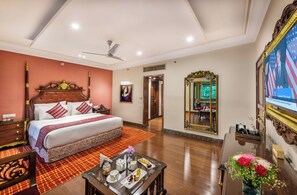 A hotel room with a large bed, a ceiling fan, a television, a mirror, and a dining table with a tray of food. - Mayfair Lagoon Bhubaneswar (Bhubaneshwar)