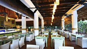 A restaurant with outdoor seating, white wicker chairs, tables with table settings, and a thatched roof. - Sandos Caracol Eco Resort - Select Club - All Incl (Playa del Carmen)