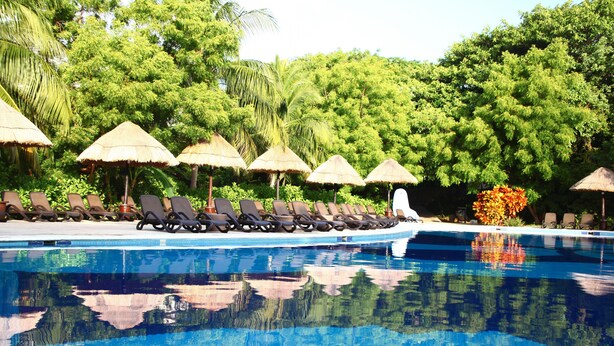 A swimming pool with lounge chairs and thatched umbrellas. - Sandos Caracol Eco Resort - Select Club - All Incl (Playa del Carmen)