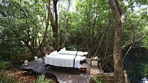A secluded forest bed with a wooden deck, two beds, and a small table with a bowl. - Sandos Caracol Eco Resort - Select Club - All Incl (Playa del Carmen)