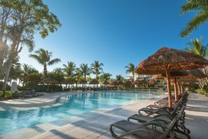 A swimming pool with lounge chairs and thatched umbrellas, surrounded by palm trees. - Sandos Caracol Eco Resort - Select Club - All Incl (Playa del Carmen)