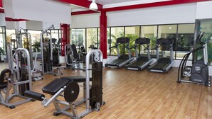 A gym with various exercise equipment, including treadmills and weight machines, with large windows and a wooden floor. - Sandos Caracol Eco Resort - Select Club - All Incl (Playa del Carmen)