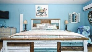 A bedroom with a bed, bedside tables, a wall-mounted TV, and a painting. - Cedar Key Turtle 132 (Cedar Key)