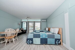 A bedroom with a large bed, a desk, and a chair. - Little Blue Anchor Condo 124 (Cedar Key)