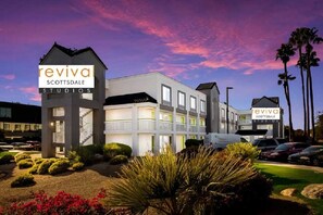 A multi-story building with 'reviva scottsdale studios' signage, a parking lot, and palm trees. - Revival Scottsdale Studios (Orlando)