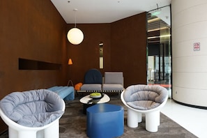 Ett modernt loungeområde med sittplatser, ett soffbord och en hängande lampa.