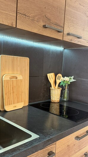 Eine Küche mit schwarzem Arbeitsplatz, einem Holzschneidebrett, einem gewebten Korb mit Besteck und einer Vase mit Blumen.