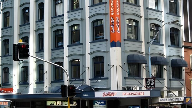 Ein mehrstöckiges Gebäude mit einem auffälligen Schild für 'Backpackers'.