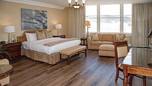 Habitación de hotel con una cama grande, un sofá, una mesa de comedor y vista a la ciudad.