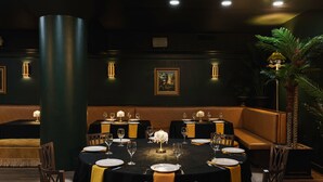 A formal dining area with round tables, chairs, and a central light fixture.