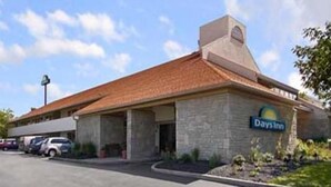 A Days Inn with a stone facade, a red-tiled roof, and a parking lot with several cars.