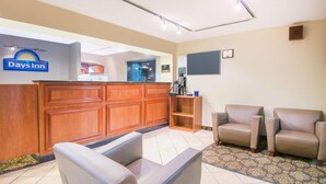 A reception area with a wooden desk, a Days Inn sign, a blackboard, and two leather armchairs.