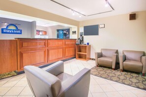 A reception area with a wooden desk, a Days Inn sign, a blackboard, and two leather armchairs. - Days Inn by Wyndham Middleburg Heights (Middleburg Heights)