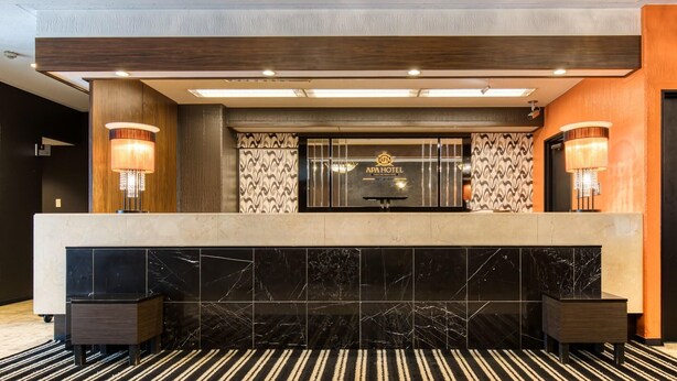 A hotel reception desk with a marble counter, two wall-mounted lamps, a chandelier, and a patterned wall. - APA Hotel Marugame-ekimae-odori (Marugame)