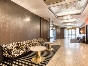Um lobby moderno com um sofá, duas mesas redondas e um lustre.