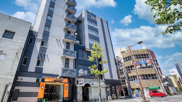 Ett hotell med flera våningar och modern design, med en tydlig skylt med texten ”APA HOTEL” vid entrén.
