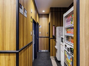 A hotel hallway with wooden walls, a vending machine, and a refrigerator. - APA Hotel Hakata-ekimae (Fukuoka)