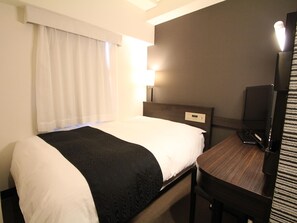 Une chambre d’hôtel équipée d’un lit, d’un bureau, d’une chaise, d’une télévision et d’une fenêtre avec des rideaux.