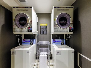 Eine Wäscherei mit zwei Maschinen, beide mit 'AQUA CO/N DRYER 45' beschriftet, und einem Metallgestell dazwischen.