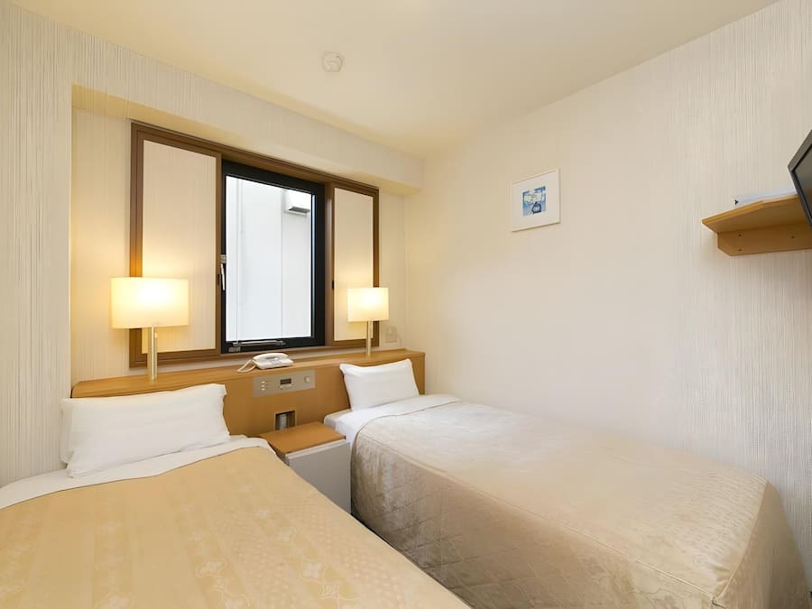 Habitación de hotel con dos camas, un televisor, un escritorio y una ventana.