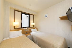 Habitación de hotel con dos camas, un televisor, un escritorio y una ventana.