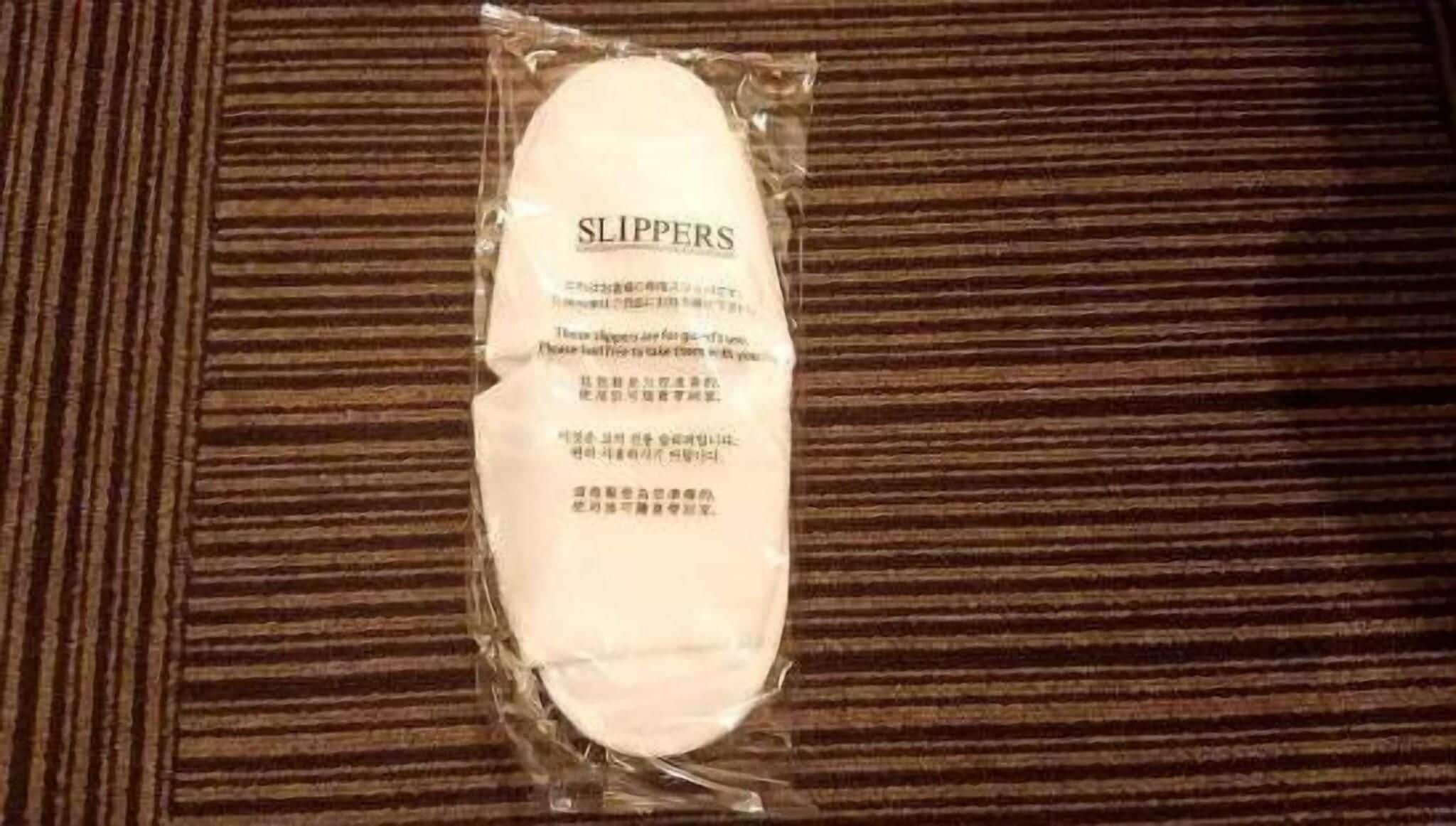 A package of slippers on a striped carpet.