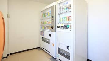 A vending machine with various drinks and snacks, a door, and a tiled floor.