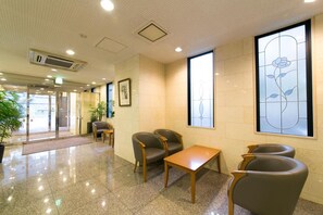 Un vestíbulo con mostrador de recepción, zona de estar y amplias ventanas con diseños florales.