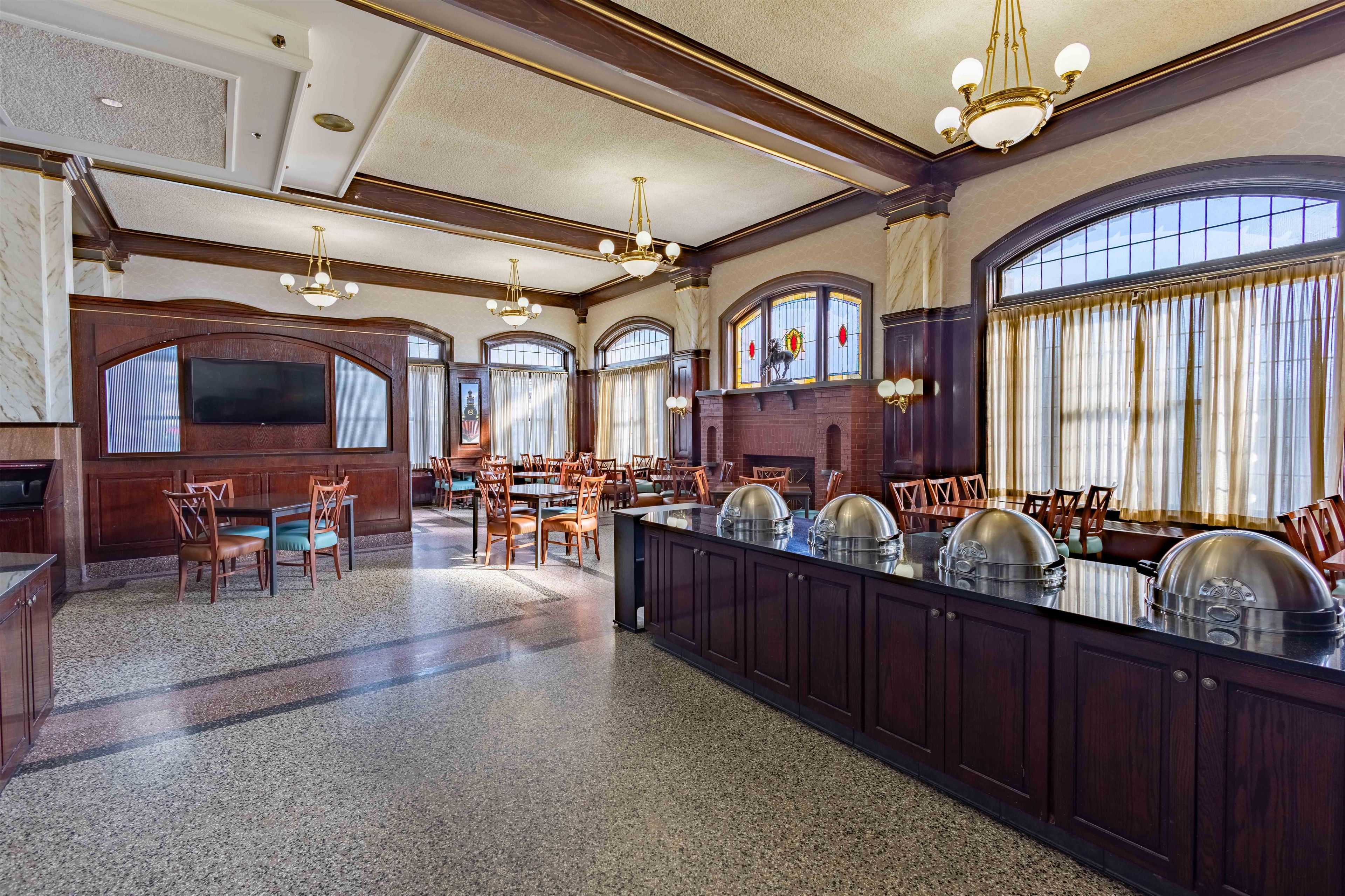 A spacious dining area with a long counter, multiple chairs, and a chandelier.