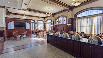 A spacious dining area with a long counter, multiple chairs, and a chandelier.