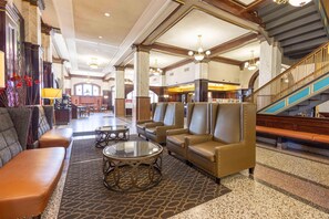 Eine Lobby mit Ledersofas, einer Treppe und einer Chandelüstere.