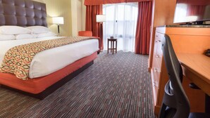 A hotel room with a large bed, a desk, a chair, a lamp, and a television. - Drury Inn Union Station (St. Louis)