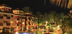 Ein Resort mit mehrstöckigen Gebäuden, einem Schwimmbad und Palmen.
