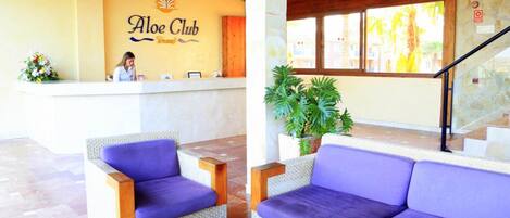 A reception area with a reception desk, a woman behind it, and purple seating.