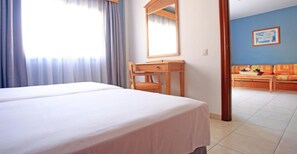 A hotel room with a bed, a desk, and a view of the adjacent living area. - O7 Aloe Corralejo (La Oliva)