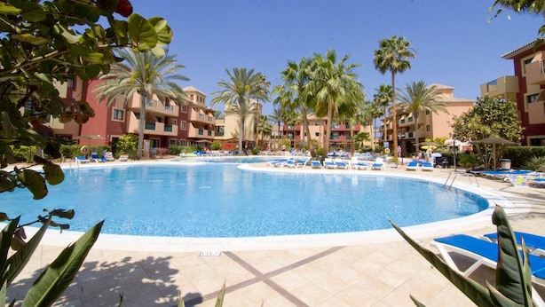 Una piscina circondata da palme e edifici con balconi.
