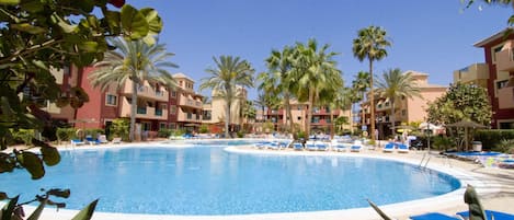 Une piscine entourée de palmiers et de bâtiments dotés de balcons.