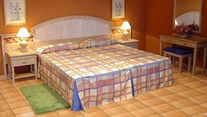 Una camera d'albergo con un letto, due comodini, un tappeto verde e uno specchio.