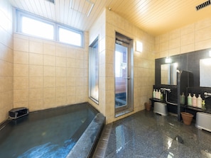 A modern bathroom with a large bathtub, a shower area, and a vanity with toiletries.