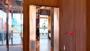 A modern hotel entrance with a wooden interior, glass doors, and a visible reception area.