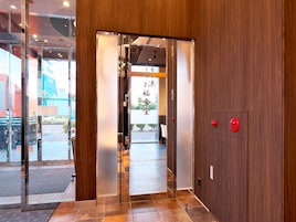 Una entrada de hotel moderna con interior de madera, puertas de cristal y una recepción visible.