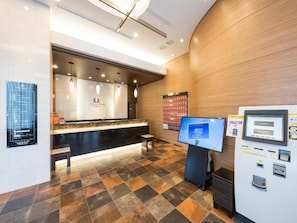 A hotel reception area with a counter, a digital display, and a vending machine.